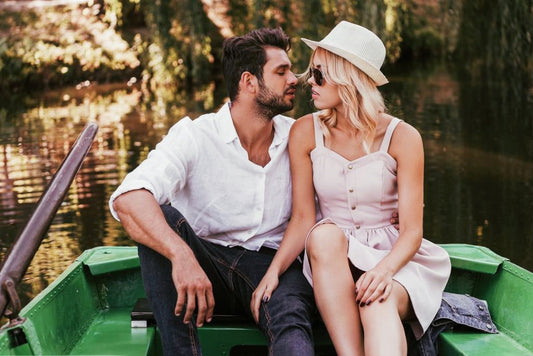 Happy young couple kissing while sitting in boat on lake 