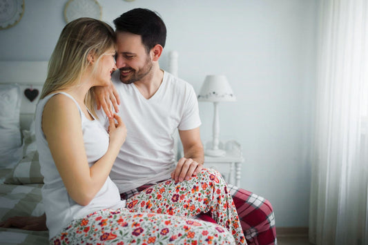 A couple looking intimately at each other from the edge of the bed